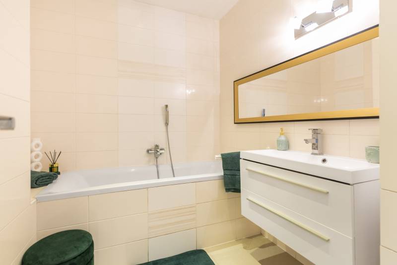 Moderný rodinný dom s bazénom v Trnave!!! - Kúpeľňa so zrkadlom, vaňou a umývadlom v rodinnom dome, svetlé dlaždice.