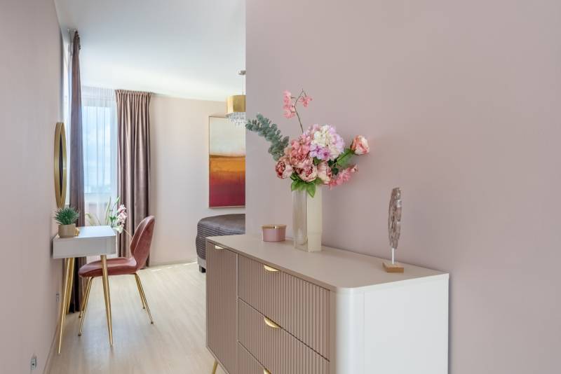 Moderný rodinný dom s bazénom v Trnave!!! - Kvetinová dekorácia na komode, zrkadlo, stolička a podlaha s dreveným dekorom v rodinnom dome.