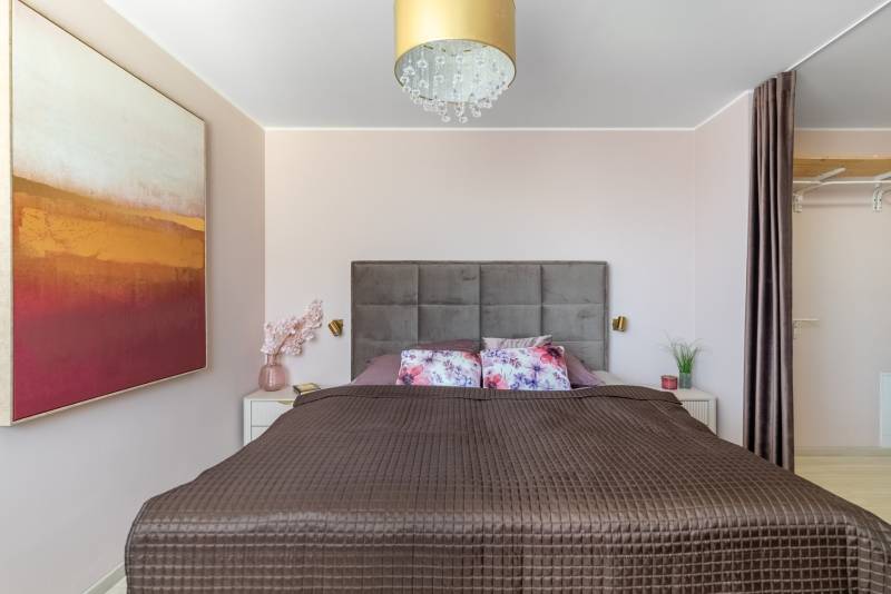 Moderný rodinný dom s bazénom v Trnave!!! - Spálňa so širokou posteľou, dekoratívnymi vankúšmi, obrazom a skrytým úložným priestorom v 4-izbovom byte.