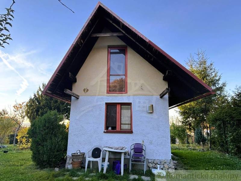 Záhrada s chatkou pod Malými Karpatami, Sološnica - Chata v Sološnici so strmou strechou, okná, príroda a plastové stoličky.