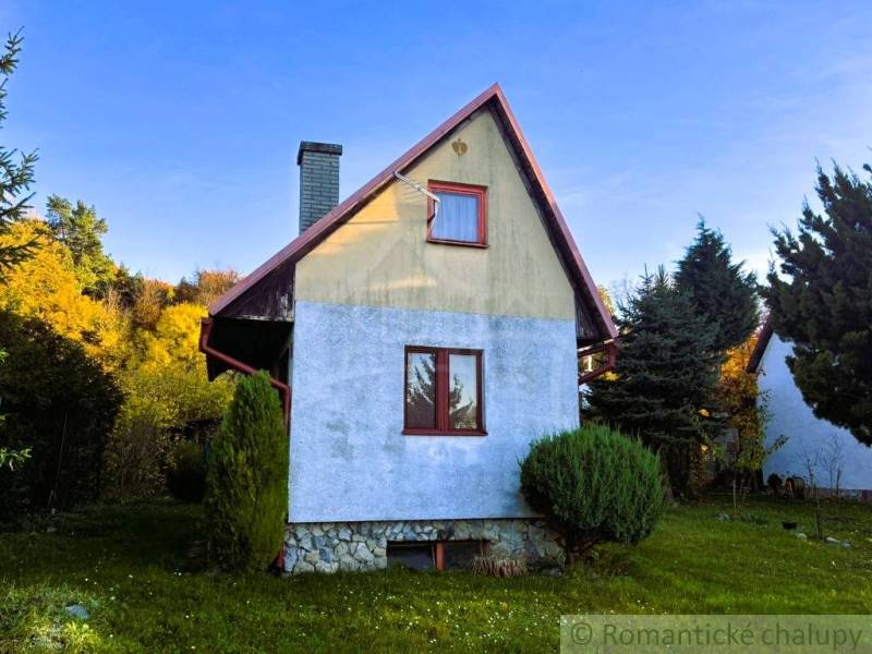 Záhrada s chatkou pod Malými Karpatami, Sološnica - Chata v Sološnici obklopená zeleňou s modrou omietkou a šikmou strechou.