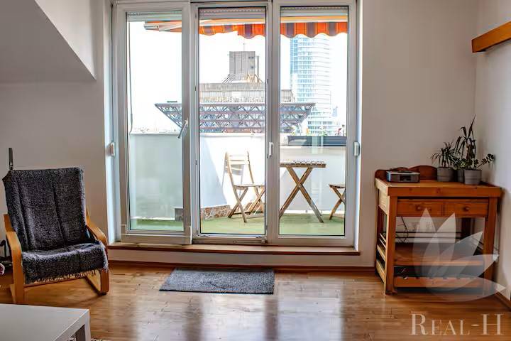 Bývanie  v Starom meste ? Jedinečná príležitosť skvelého bytu - Obývacia izba s balkónom, drevená podlaha, stolička a stolík v 3-izbovom byte.