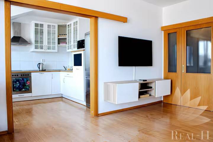 Bývanie  v Starom meste ? Jedinečná príležitosť skvelého bytu - Obývacia izba v 3-izbovom byte s prechodom do kuchyne a nástennou televíziou.