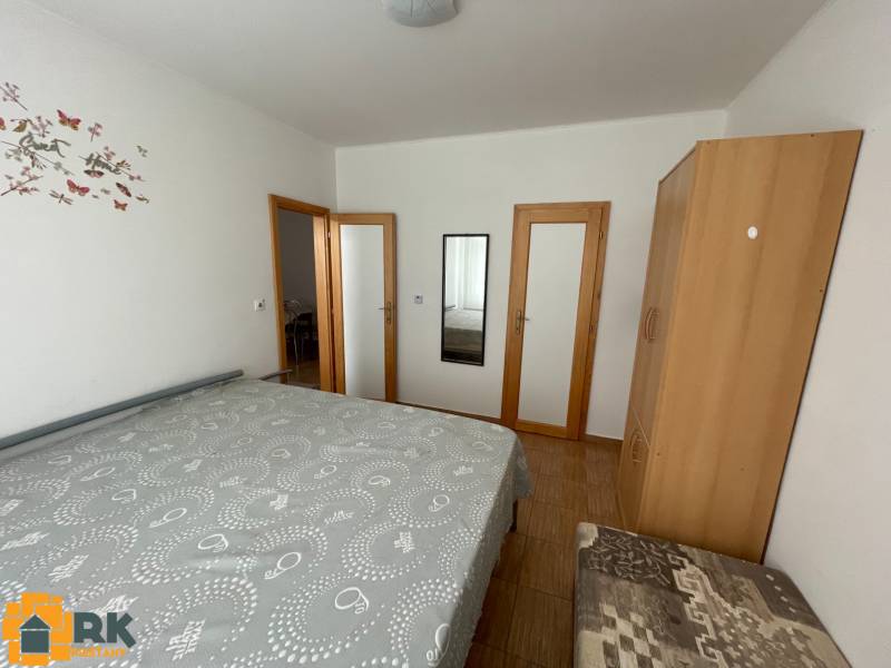 Predaj budovy v centre mesta - Spálňa s posteľou, skriňou a zrkadlom v rodinnom dome s podlahou s dreveným dekorom.