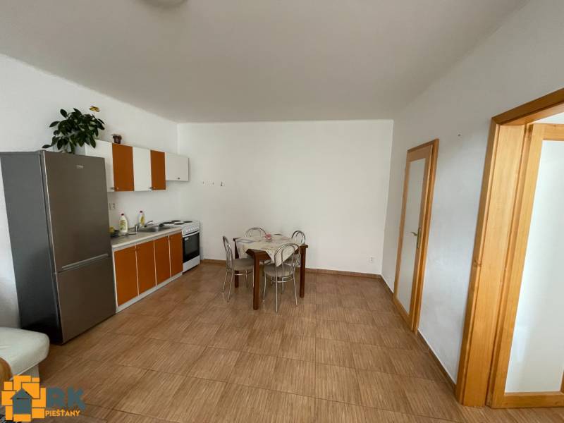 Predaj budovy v centre mesta - Kuchyňa v rodinnom dome s dlažbou a jedálenským stolom.