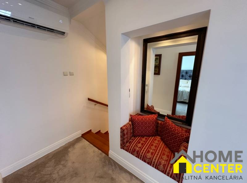 PREDAJ : ŠTÝLOVÝ RODINNÝ DOM S BAZÉNOM, KOMÁRNO - Rodinný dom zobrazuje schody s dreveným dekorom, zrkadlo a sedací kútik s vankúšmi.