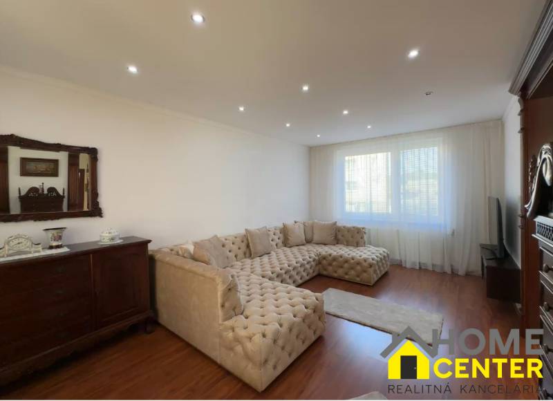 PREDAJ : ŠTÝLOVÝ RODINNÝ DOM S BAZÉNOM, KOMÁRNO - Obývacia izba s veľkou sedačkou, podlahou s dreveným dekorom a starožitným nábytkom.