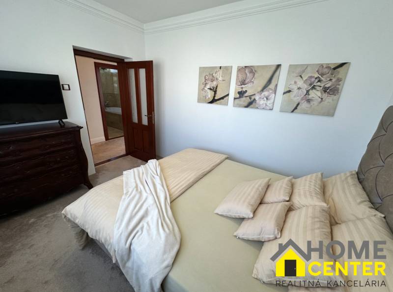 PREDAJ : ŠTÝLOVÝ RODINNÝ DOM S BAZÉNOM, KOMÁRNO - Spálňa rodinného domu s dekoračnými obrazmi na stene, čalúneným nábytkom a dverami.