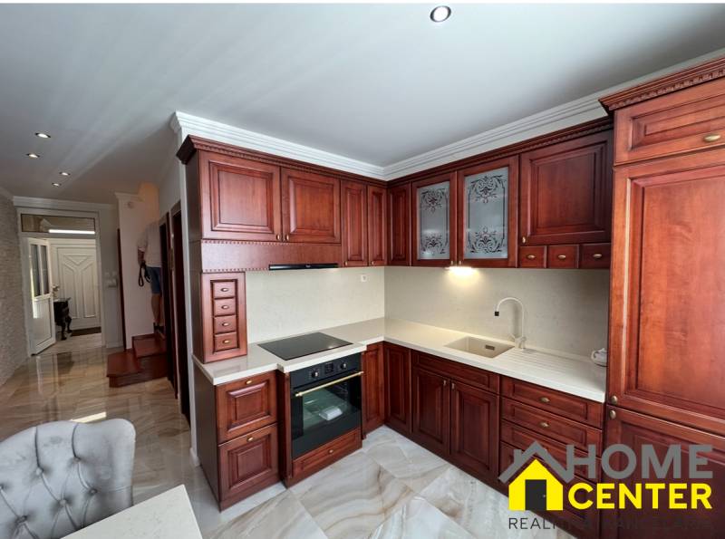 PREDAJ : ŠTÝLOVÝ RODINNÝ DOM S BAZÉNOM, KOMÁRNO - Kuchyňa s tmavými drevenými skrinkami a podlahou s dreveným dekorom v rodinnom dome.