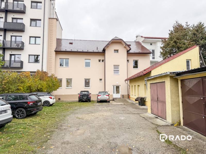 Na predaj ambulancia 101m2, Bratislavská ul. - Žilina - Budova na Bratislavskej ulici v Žiline, obklopená autami a garážami, vhodná pre kancelárie.