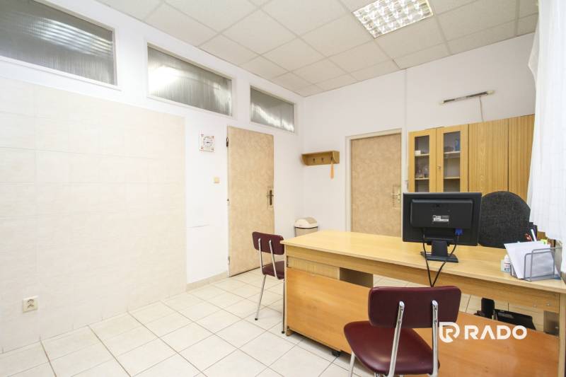 Na predaj ambulancia 101m2, Bratislavská ul. - Žilina - Kancelárie so stolom, stoličkou, počítačom a skriňou na svetlej keramickej podlahe.