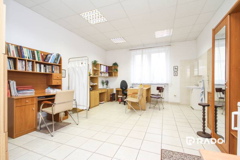 Na predaj ambulancia 101m2, Bratislavská ul. - Žilina - Kancelárie so stolmi a stoličkami, biela keramická podlaha, police s knihami.