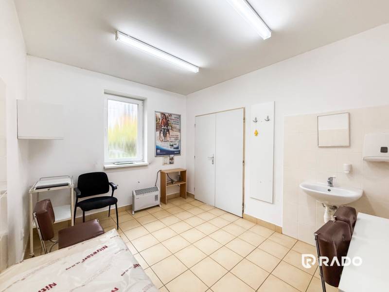 Na predaj ambulancia 101m2, Bratislavská ul. - Žilina - Ordinácia s umývadlom, stoličkami a oknom s výhľadom, podlaha s bledým dekorom.