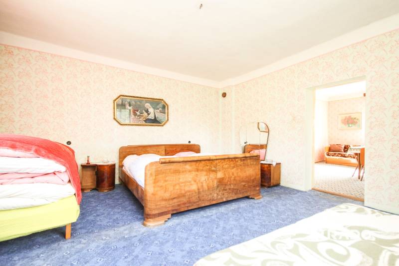 5i RD s garážou, Čierna Lehota, okr. Bánovce n./B. - Spálňa v rodinnom dome s dreveným nábytkom a bohatým vzorovaným kobercom.