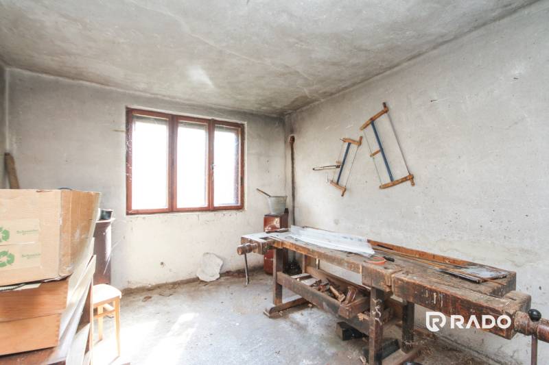 5i RD s garážou, Čierna Lehota, okr. Bánovce n./B. - Dielňa v rodinnom dome s pracovným stolom a píla na stene.