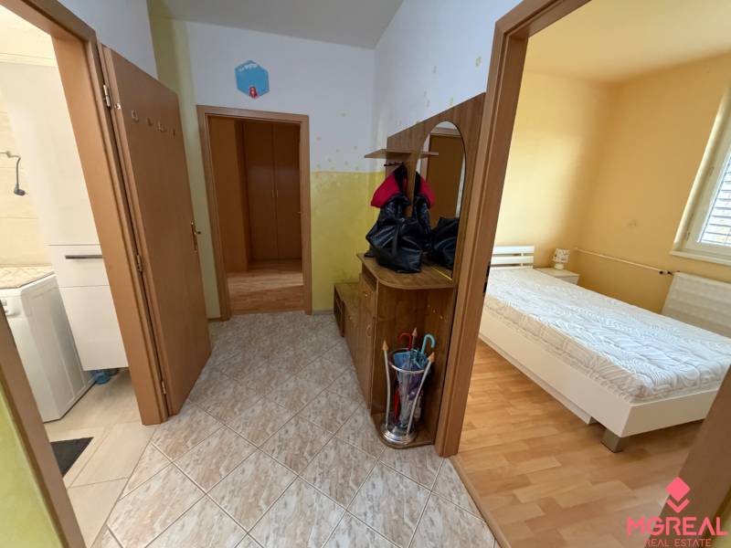 3 izbový byt  balkónom Topoľčany Juh - Chodba v 3-izbovom byte s dlažbou, vstupom do kúpeľne a spálne s dreveným dekorom podlahy.