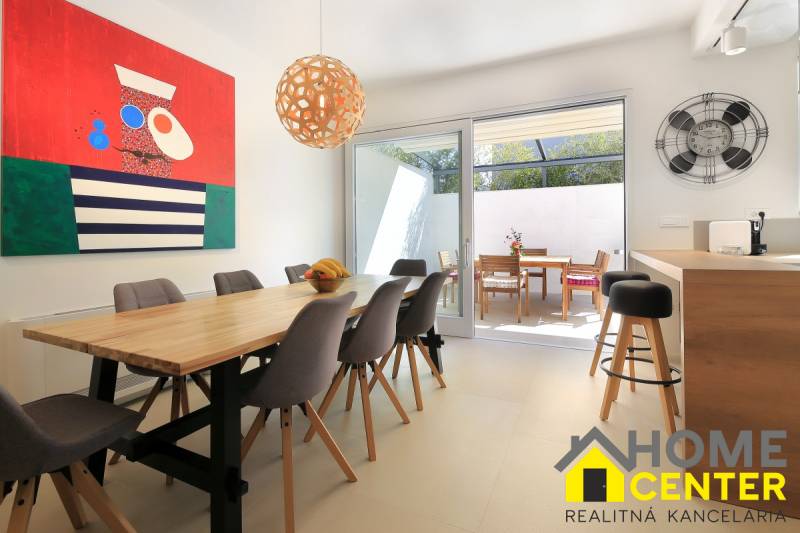 NA PREDAJ moderná vila /251 m²/ v atraktívnej lokalite, ostrov Krk - Svetlá jedáleň vo Vile s dreveným stolom, farebným obrazom a terasou.