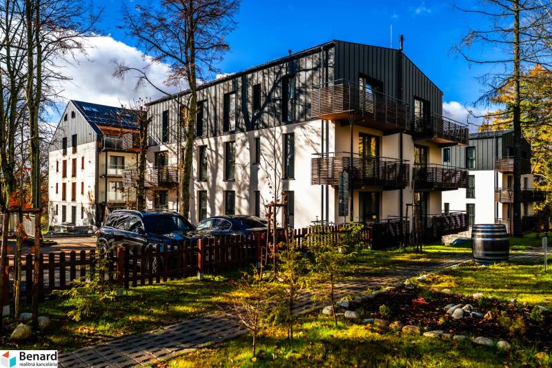 Na predaj krásny apartmám v Štrbe - Exteriér bytového domu na Lúčnej ulici v Štrbe so zaparkovanými vozidlami a upraveným okolím.