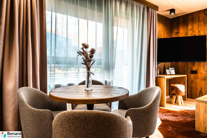 Na predaj krásny apartmám v Štrbe - Jedálenský kút v 2-izbovom byte s podlahou s dreveným dekorom a výhľadom z okna.