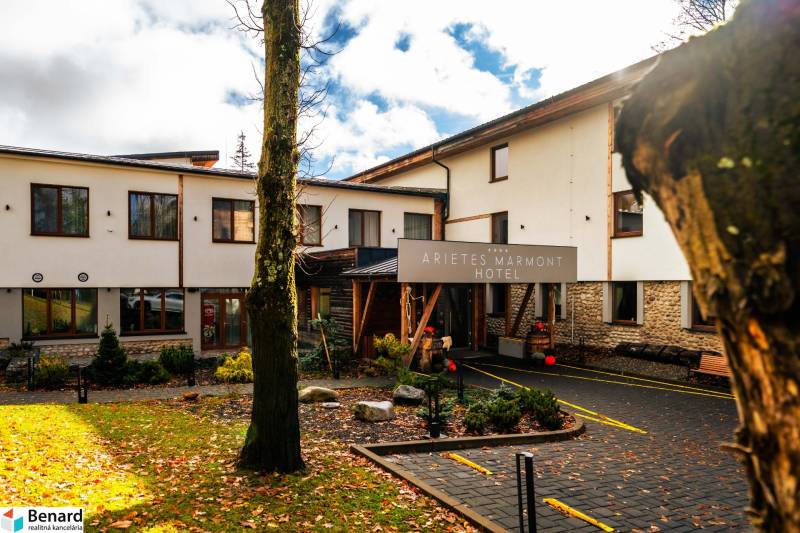 Na predaj krásny apartmám v Štrbe - Budova hotela so stromami a padajúcim lístím v Štrbe na ulici Lúčna.