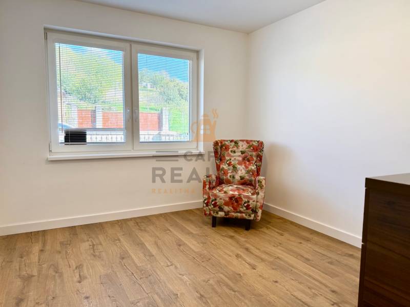 REZERVOVANÉ Na prenájom 4 izbový rodinný dom, Pata, ul. Pod Vinohradmi - Izba s podlahou s dreveným dekorom, kvetinovým kreslom a oknom orientovaným von.