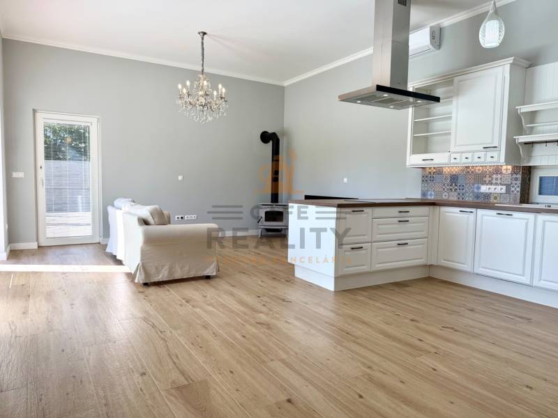 REZERVOVANÉ Na prenájom 4 izbový rodinný dom, Pata, ul. Pod Vinohradmi - Obývacia izba s kuchyňou v rodinnom dome, s podlahou s dreveným dekorom a krbom.