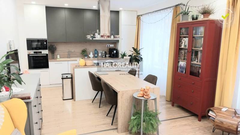 Predaj, trojizbový byt Komárno - Interiér kuchyne v 3-izbovom byte s jedálenským stolom a podlahou s dreveným dekorom.