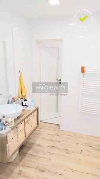 Predaj, trojizbový byt Komárno - Kúpeľňa s podlahou s dreveným dekorom, umývadlom na doske a bielymi stenami v 3-izbovom byte.