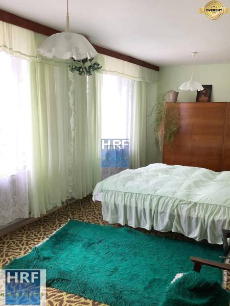 Na predaj rod. dom v obci Radošovce - Vieska, okr. Skalica. - Spálňa v rodinnom dome s kobercami, záclonami a drevenou skriňou.