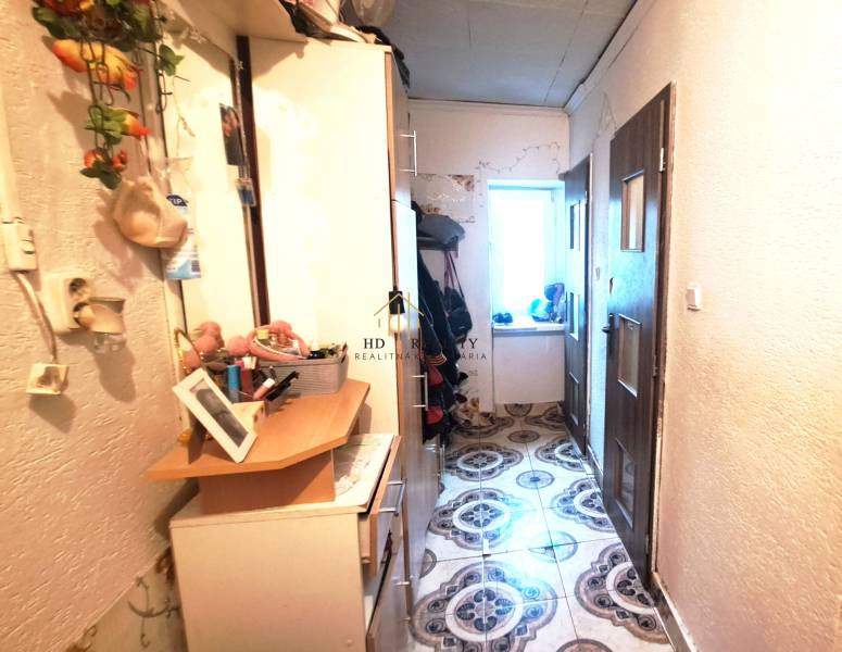 HD reality, Predaj 2-izbového bytu, Veľký Krtíš - Chodba so skrinkami a dekoráciami v 2-izbovom byte. Vľavo vešiaky, vpravo dvere.