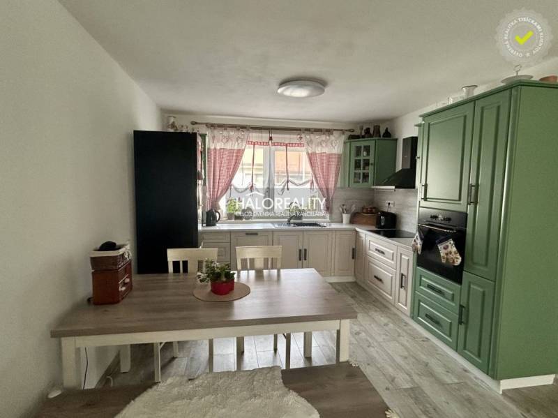 REZERVOVANÉ - Predaj, rodinný dom Malinová - NOVOSTA... - Kuchyňa v rodinnom dome so zelenou linkou, jedálenským stolom a červenými závesmi.