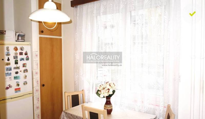 Predaj, trojizbový byt s vlastnou garážou Malacky, C... - Kuchyňa v 3-izbovom byte s chladničkou a stolom, kde sú kvety vo váze.