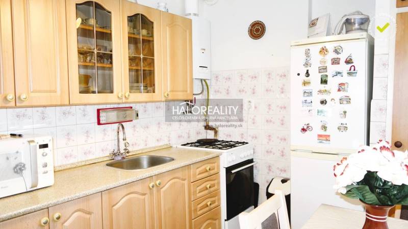 Predaj, trojizbový byt s vlastnou garážou Malacky, C... - Kuchyňa v 3-izbovom byte s dreveným dekorom, mikrovlnkou a chladničkou.