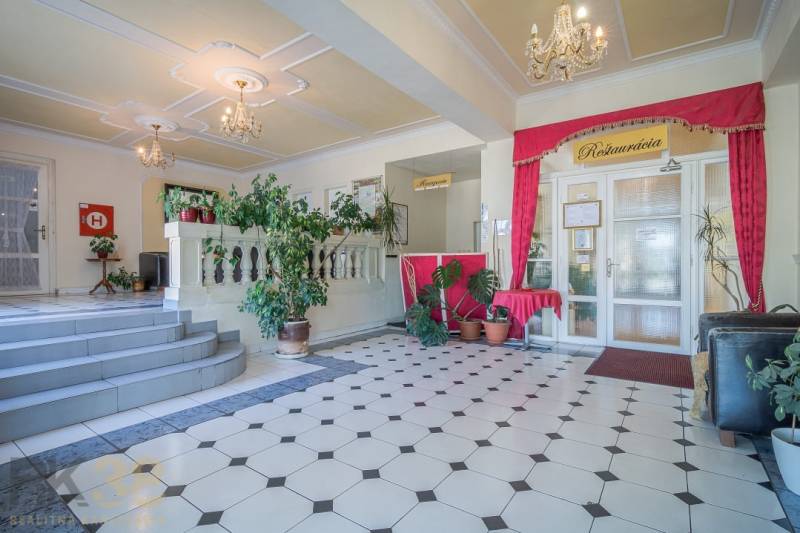 Predaj nehnuteľnosti v mestskej časti Poprad-Veľká - Hotelová recepcia s rastlinami a lustrami, dlažba s geometrickým vzorom.