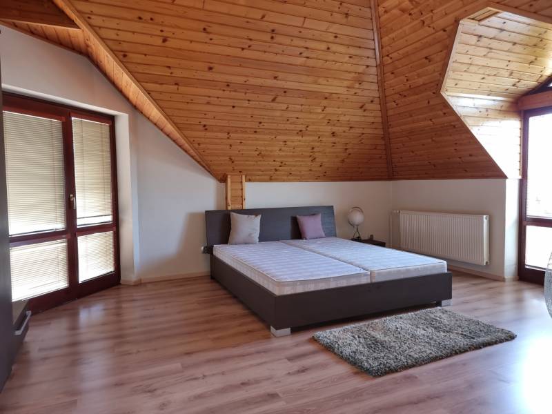 EXKLUZÍVNA VILA - NITRA - PREDAJ - Podkrovná spálňa v rodinnom dome s dreveným obložením, strešnými oknami a posteľou.