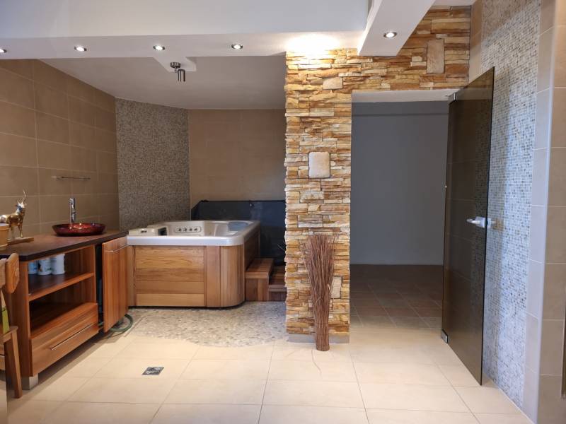 EXKLUZÍVNA VILA - NITRA - PREDAJ - Kúpeľňa v rodinnom dome s vírivkou, dreveným nábytkom a kamenným obkladom.