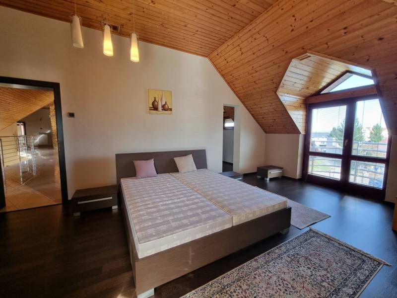 EXKLUZÍVNA VILA - NITRA - PREDAJ - Podkrovná spálňa v rodinnom dome s dreveným obkladom a dvojposteľou.