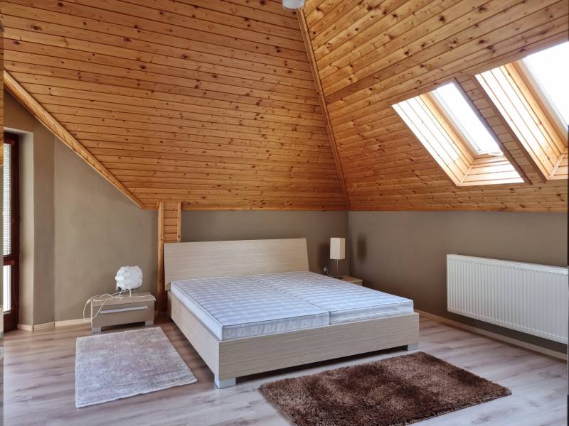EXKLUZÍVNA VILA - NITRA - PREDAJ - Podkrovná spálňa s dreveným stropom a strešnými oknami v rodinnom dome.