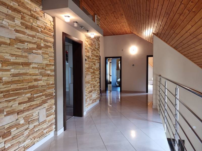 EXKLUZÍVNA VILA - NITRA - PREDAJ - Chodba s kamenným obkladom, dreveným stropom a nerezovým zábradlím v rodinnom dome.