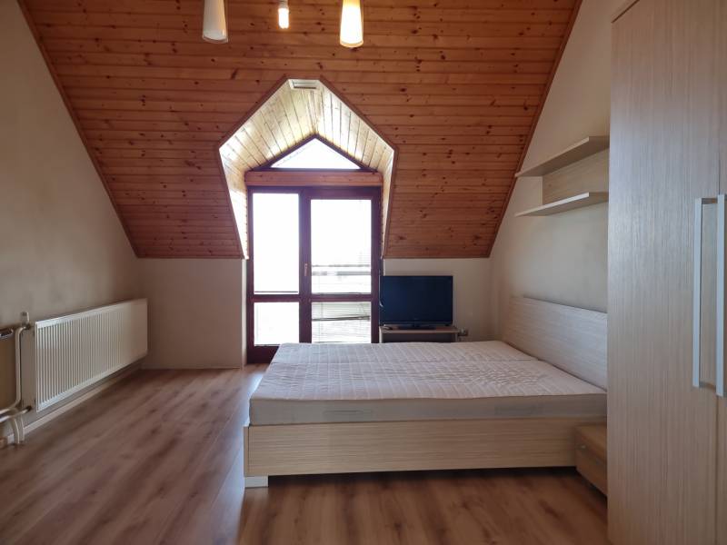 EXKLUZÍVNA VILA - NITRA - PREDAJ - Podkrovná izba v rodinnom dome s drevenými stropmi a posteľou.