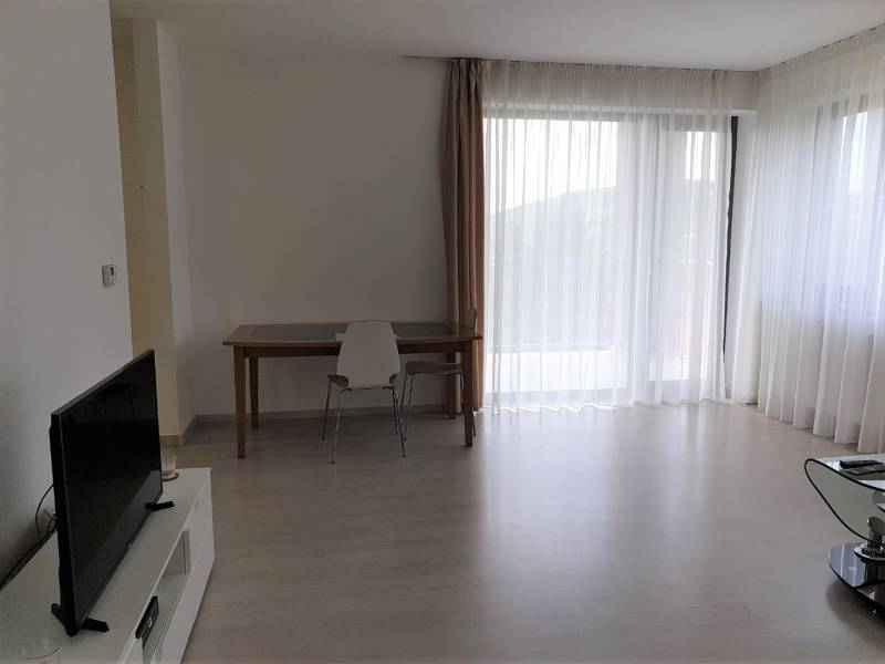 PRENÁJOM - Byt s krásnym výhľadom - Nitra, Dolnohorská - Svetlá obývačka v 2-izbovom byte s pohovkou, stolom a televízorom na podlahe s dreveným dekorom.