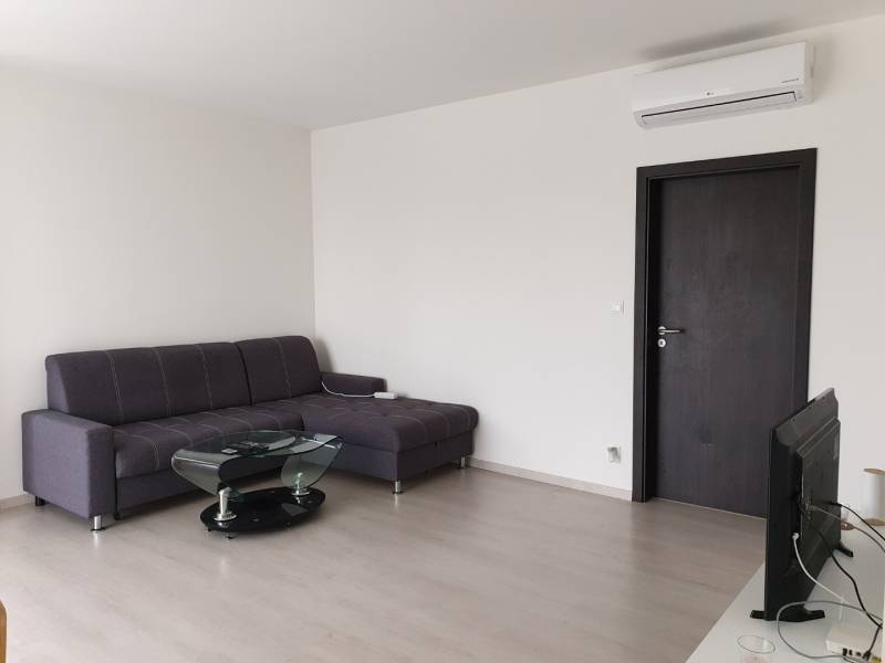 PRENÁJOM - Byt s krásnym výhľadom - Nitra, Dolnohorská - Obývacia izba v 2-izbovom byte so sivou sedačkou a podlahou s dreveným dekorom.