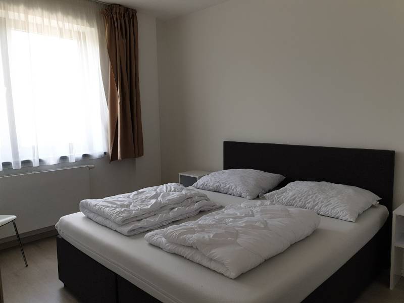 PRENÁJOM - Byt s krásnym výhľadom - Nitra, Dolnohorská - Spálňa v 2-izbovom byte s jednoduchou posteľou a svetlými závesmi.