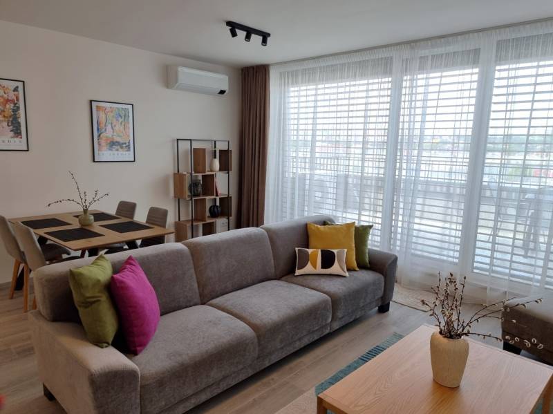 PRENÁJOM - 3 izbový byt Nitra – RIVIERA NITRA, Piesková ulica - Obývacia izba s pohovkou, jedálenským stolom a policami v 3-izbovom byte.