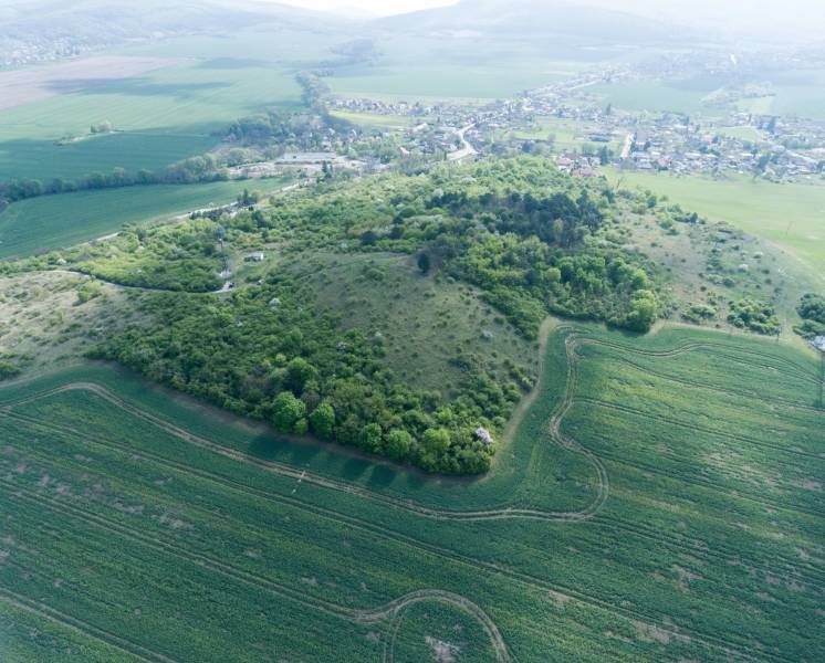 PREDAJ - Pozemok s krásnymi výhľadmi v lesnom prostredí - Podhorany - Letecký pohľad na zelené pozemky a okolitú krajinu využívanú na bývanie.