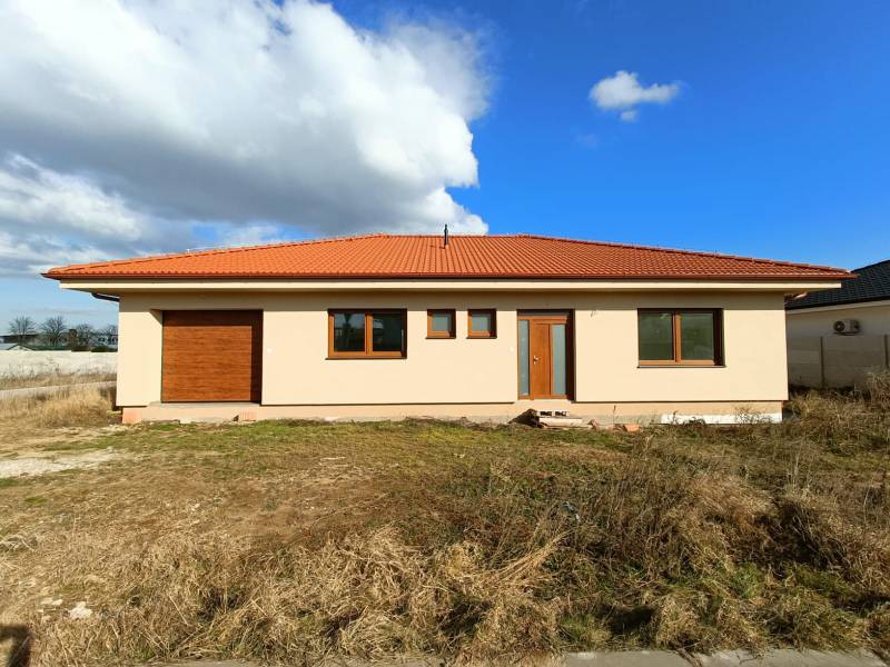 PREDAJ - 4 izbový holodom s veľkou garážou , Lužianky, Smreková ulica - Rodinný dom s červenou škridlovou strechou na trávnatom pozemku pod modrou oblohou.