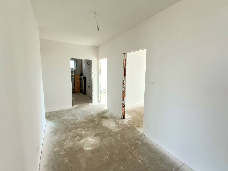 PREDAJ - 4 izbový holodom s veľkou garážou , Lužianky, Smreková ulica - Chodba s bielymi stenami v rodinnom dome, pred rekonštrukciou, s pohľadom na ďalšiu miestnosť.