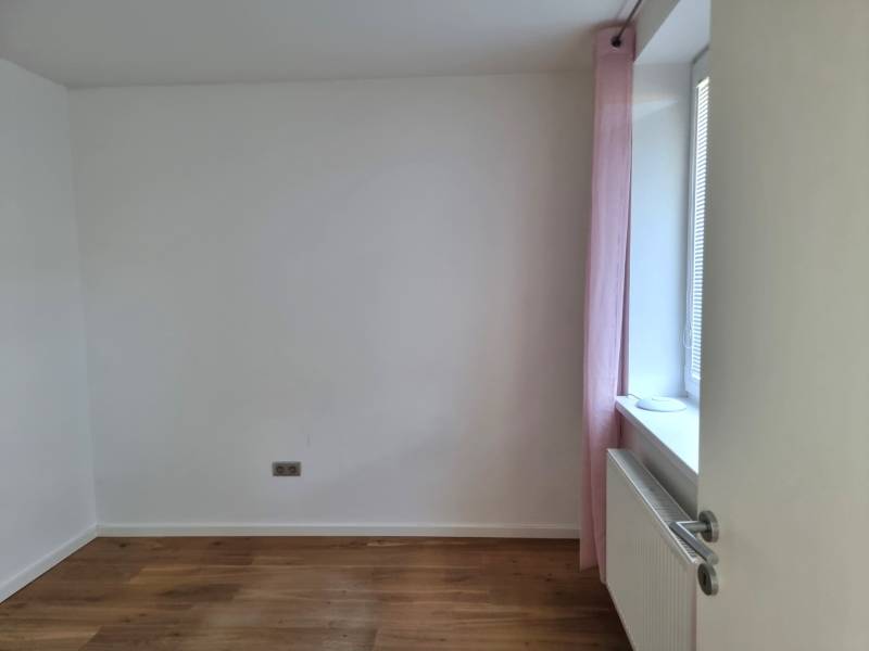 PREDAJ - 3 izbový dom v centre mesta, Nitra - Izba v rodinnom dome s podlahou s dreveným dekorom a svetloružovým závesom.