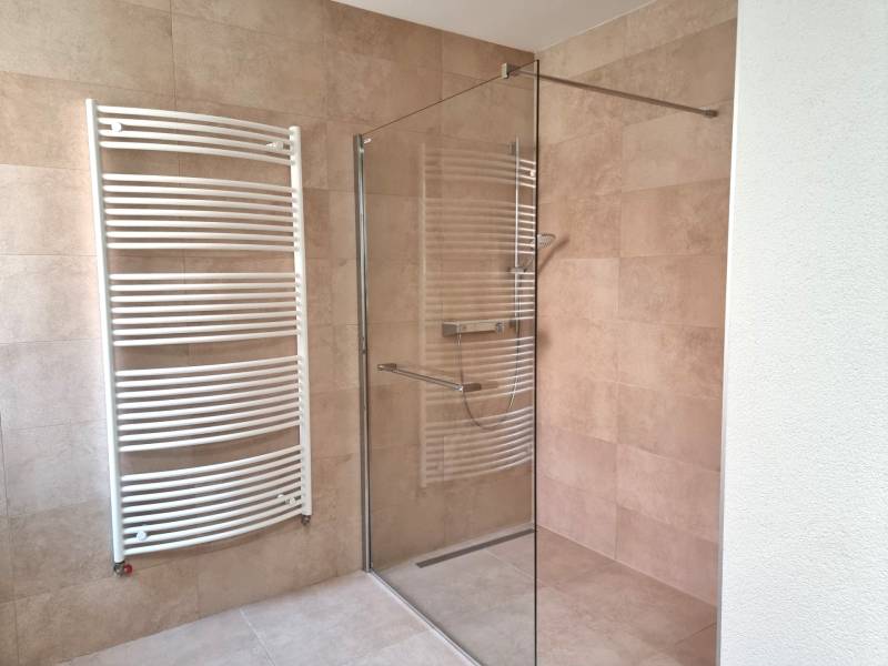 PREDAJ - 3 izbový dom v centre mesta, Nitra - Sprchový kút a radiátor v kúpeľni rodinného domu s keramickým obkladom.