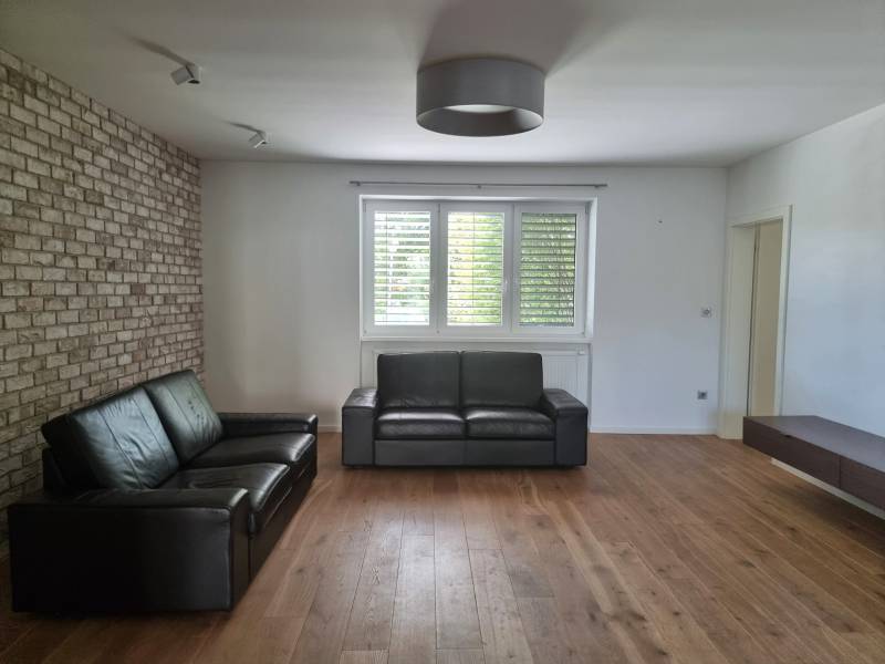 PREDAJ - 3 izbový dom v centre mesta, Nitra - Obývačka v rodinnom dome s koženým sedením, tehlovou stenou a podlahou s dreveným dekorom.